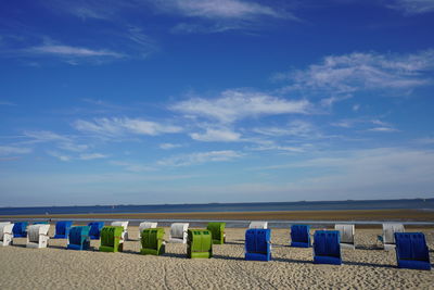 Hooded chairs on beach against blue sky