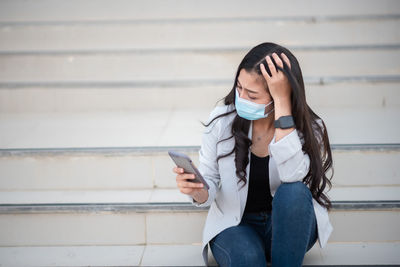 Young woman using mobile phone while sitting on steps