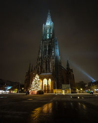 Illuminated church with christmas tree against sky at night