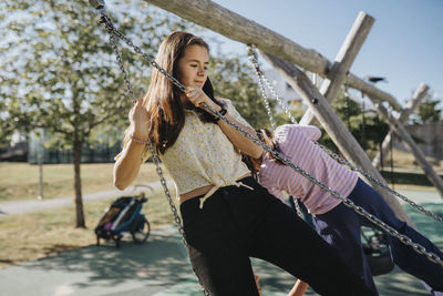 Sisters having fun swinging on swing on playground