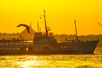 Nautical vessel in sea against orange sky