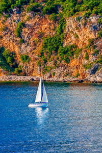 Sailboat sailing on sea against mountain