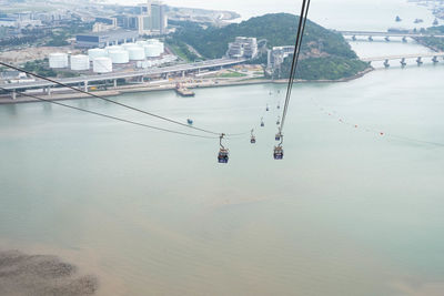 High angle view of overhead cable cars over sea by buildings