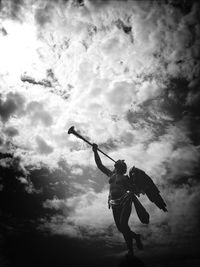 Low angle view of woman standing against cloudy sky