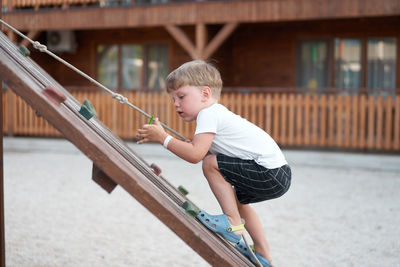 Boy holding umbrella against built structure