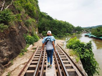 Rear view of man standing on footbridge against sky