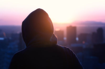 Close-up of silhouette person wearing hooded shirt against sky during sunset