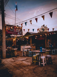 Chairs and tables at restaurant against sky at dusk