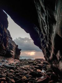 Rock formation on beach against sky during sunset