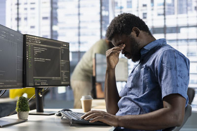 Side view of young man using mobile phone in office