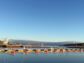 Sailboats moored in sea against clear blue sky