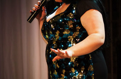 Midsection of woman singing on stage