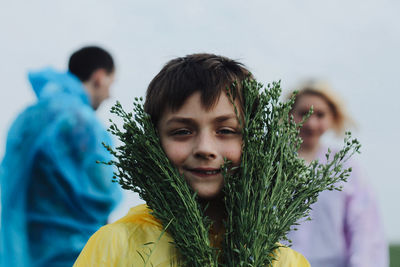 Portrait of happy boy holding plants