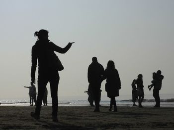 Silhouette people on beach against clear sky