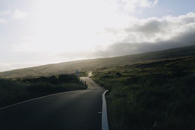 Road leading towards landscape against sky