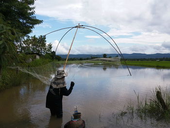 Man standing by river against sky