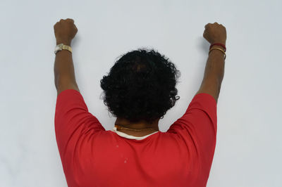 Rear view of woman with arms raised against white background