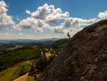 Side view of person standing on mountain against sky