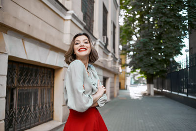 Portrait of smiling young woman standing against building