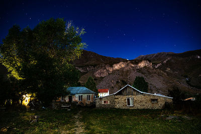 House and trees on mountain against sky at night