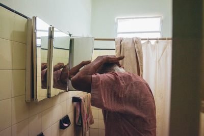 Rear view of woman looking through window