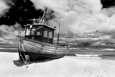 Boat moored on beach against sky