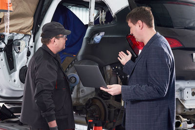 Businessman standing with mechanic in garage