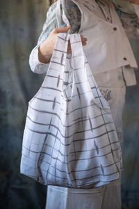 Midsection of woman standing against white wall