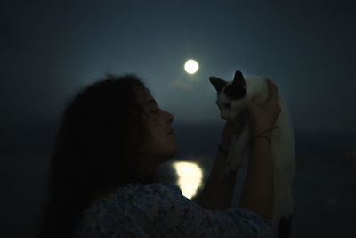 Side view of woman with dog at night