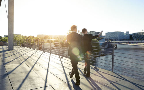 Two businessmen walking on a bridge in the city