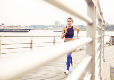 Woman running while exercising on bridge in city