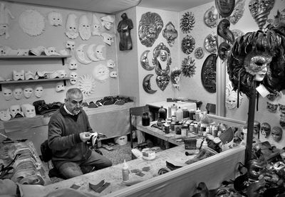 High angle view of man sitting in masks store