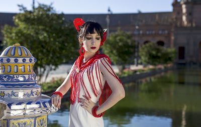 Young woman in traditional clothes standing by lake in city