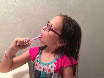 Girl brushing teeth against wall