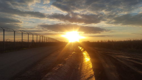 Country road against cloudy sky during sunset