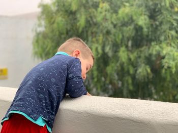 Side view of boy leaning on concrete wall