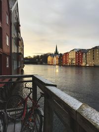 View of buildings by river against cloudy sky