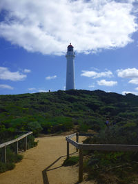 Lighthouse by street amidst buildings against sky