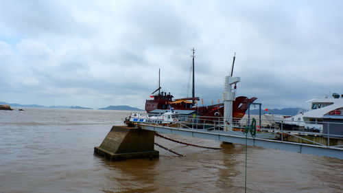 Fishing boat moored at harbor against sky