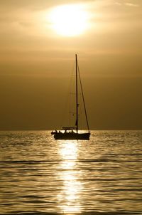 Sailboat sailing in sea at sunset