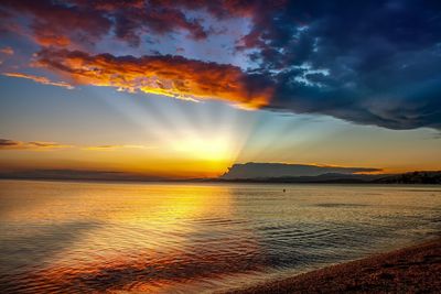 Scenic view of sea against dramatic sky during sunset