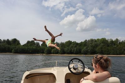 Man jumping in lake against sky