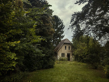 House amidst trees and buildings against sky