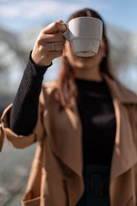 Midsection of woman holding coffee cup