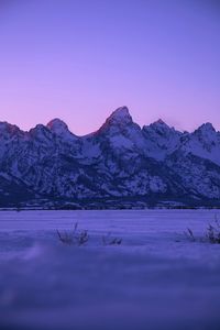 Scenic view of lake and snowcapped mountains against sky at sunset