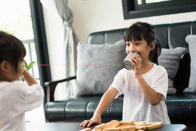 Siblings playing with tin can phones at home