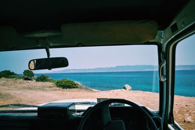 Scenic view of sea seen through off-road vehicle windshield