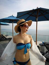 Woman wearing sunglasses and blue bikini against sea