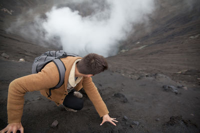 High angle view man looking down while climbing volcanic mountain