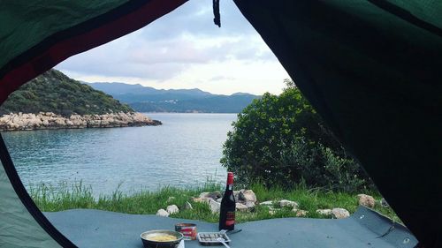 Scenic view of sea by mountains against sky